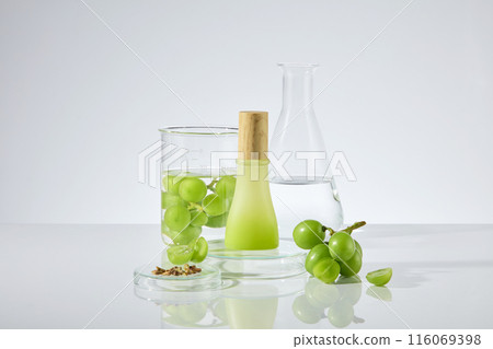 In the center of white laboratory table top displaying laboratory, fresh green grape and grape seed, which surround an unlabeled bottle has wooden lid. Photo of front view with blank space to design In the center of white laboratory table top displaying laboratory, fresh green grape and grape seed, which surround an unlabeled bottle has wooden lid. Photo of front view with blank space to design 116069398