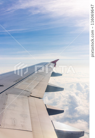 View from the airplane window at a beautiful cloudy sky and the airplane wing 116069647