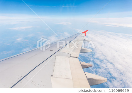 View from the airplane window at a beautiful cloudy sky and the airplane wing View from the airplane window at a beautiful cloudy sky and the airplane wing 116069659