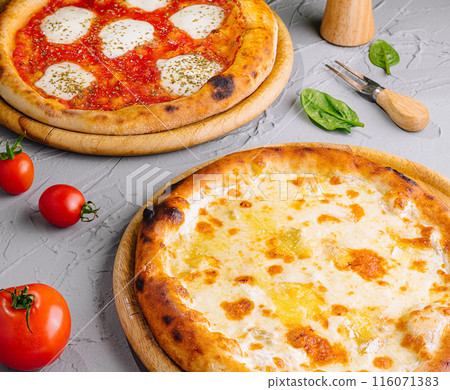 Gourmet margherita and cheese pizzas on rustic table 116071383