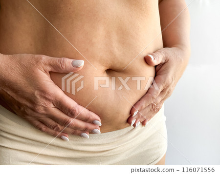 Close up of belly with hands gently touching in beige underwear on white background. Maternity and motherhood concept. Design for healthcare, postpartum care, wellness 116071556