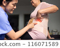 Physiotherapist checking senior women patient orthopedic corset at clinic 116071589