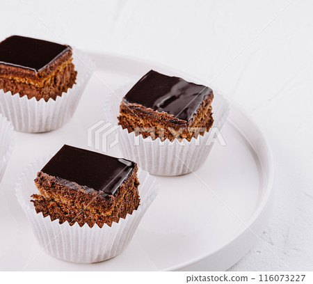 Chocolate glazed mini cakes on white plate 116073227