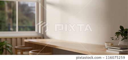 A close-up image of a long wooden table with stools in a contemporary, minimalist room. 116075259