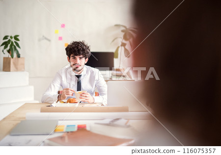 Businessman having quick lunch, fastfood meal in startup company office. Working in co-working space. Businessman having quick lunch, fastfood meal in startup company office. Working in co-working space. 116075357
