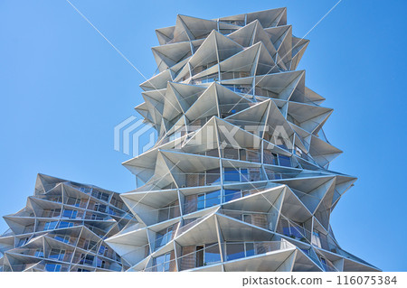 Modern residential building with geometric design against clear blue sky. City architecture with protruding triangular elements against clear blue sky 116075384