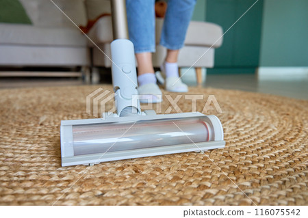 Close up of vacuum cleaner brush cleaning carpet on floor. Woman using portable cordless vacuum cleaner. Daily routine and household chores Close up of vacuum cleaner brush cleaning carpet on floor. Woman using portable cordless vacuum cleaner. Daily routine and household chores 116075542
