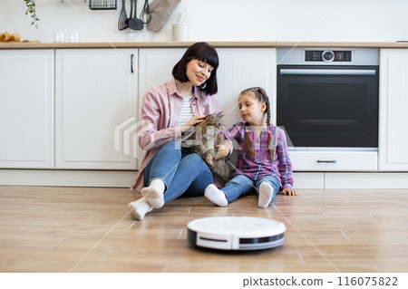 Mother and daughter with cat in modern kitchen with robot vacuum Mother and daughter with cat in modern kitchen with robot vacuum 116075822