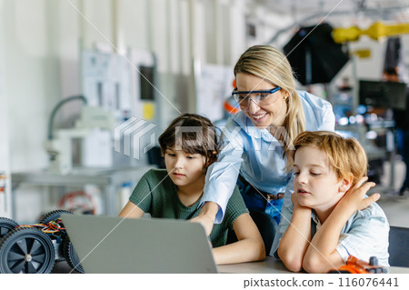 Children learning robotics in Elementary school. Young students programming, building robot in after school robotics club. Field trip to real robotics laboratory. 116076441