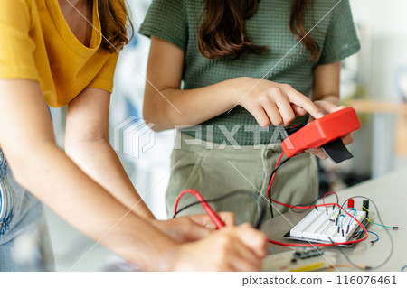 School girls working on circuit board of small robot, building robotic car in after-school robotics club. Children learning robotics in Elementary school. Girls in science. 116076461
