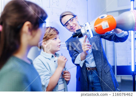 Mom and children during take your kid to work day, encouraging them in career in robotics, showing them robotic arm. Field trip to real robotics laboratory. Real scientist talking with schoolboy. Mom and children during take your kid to work day, encouraging them in career in robotics, showing them robotic arm. Field trip to real robotics laboratory. Real scientist talking with schoolboy. 116076462