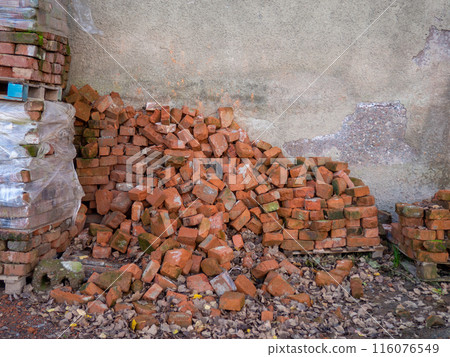 Pile of old red bricks. Forgotten building material. A pile of stones. Unfinished construction. 116076549