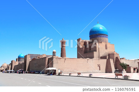 Dome with azure tile of Poi Kalyan Mosque and Kalyan minaret, religious complex of Chor Bakr, Bukhara, Uzbekistan. On blue sky background Dome with azure tile of Poi Kalyan Mosque and Kalyan minaret, religious complex of Chor Bakr, Bukhara, Uzbekistan. On blue sky background 116076591