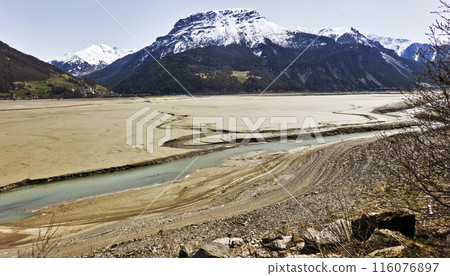 Dry bed at the foot of snow-capped mountains 116076897