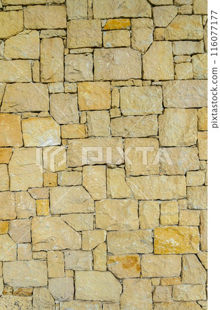 real stone wall made of yellow stone 1 116077177