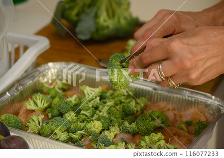 woman cutting broccoli into chicken fillet for baking 8 116077233