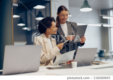 Stylish female executives managers discussing financial accounting papers and using digital tablet Stylish female executives managers discussing financial accounting papers and using digital tablet 116080605
