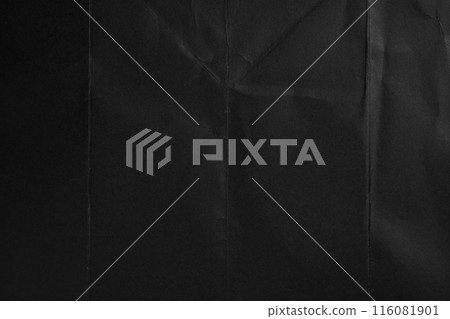 Cardboard sheet with black textured creased surface revealing subtle light reflections and creating a dark abstract design 116081901