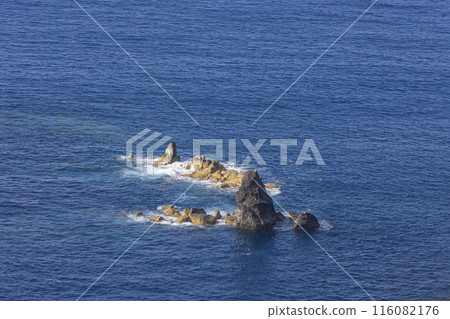 A rocky island sits in the middle of the ocean 116082176