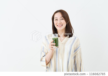 Middle-aged woman drinking green juice Middle-aged woman drinking green juice 116082785