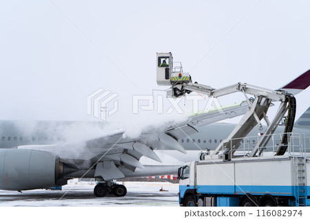 De-icing the aircraft before the flight. The deicing machine sprinkles the wing of a passenger plane with antifreeze. Winter at the airport. Snow. Aviation handling. Steam. Airport service 116082974
