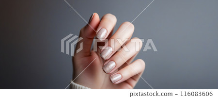 Close-up view of well-manicured hand with soft beige nails, set against grey backdrop, exemplifying elegance and modern beauty trends Close-up view of well-manicured hand with soft beige nails, set against grey backdrop, exemplifying elegance and modern beauty trends 116083606