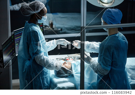Portrait of two surgeons wearing full protective clothing working in operating theater and performing surgery 116083942