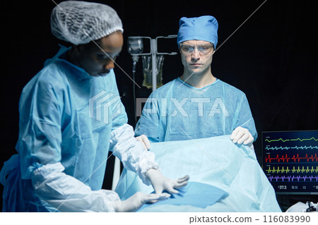 Waist up portrait of medical team of two people preparing patient for surgery in operating room copy space 116083990