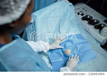 High angle view of medical assistant covering surgical site with draping in operating room copy space High angle view of medical assistant covering surgical site with draping in operating room copy space 116083994