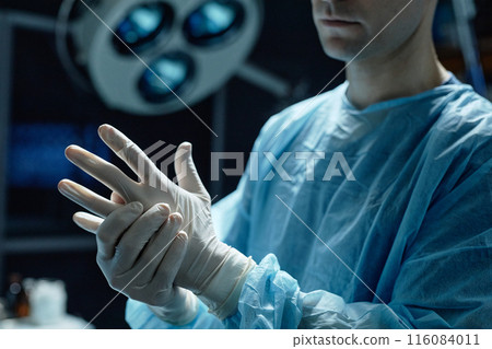 Cropped shot of surgeon wearing protective gloves preparing for surgery in operating room copy space Cropped shot of surgeon wearing protective gloves preparing for surgery in operating room copy space 116084011