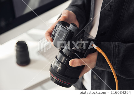 Close up shot of male hands holding professional camera and looking at photographs at camera screen, copy space 116084294