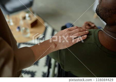 Close up of caring female therapist laying hand on shoulder of army veteran during support session on mental health copy space 116084429