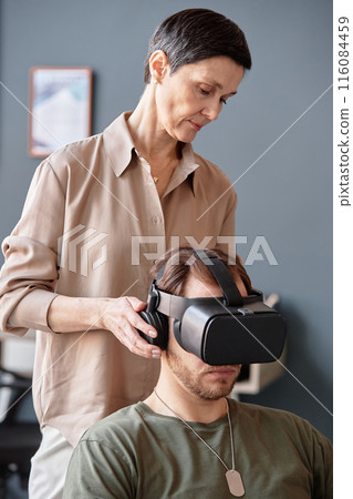 Minimal portrait of mature female psychologist using VR technology in therapy session for army veterans struggling with PTSD Minimal portrait of mature female psychologist using VR technology in therapy session for army veterans struggling with PTSD 116084459