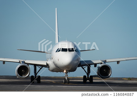 White plane to runway for take off, airplane taxiing for take off. White passenger jet plane taxiing along the runway in the airport 116084887