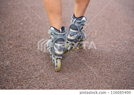 Close up view of feet in inline skates of roller skater woman. Rollerblading in park. Outdoor activities. Summer roller skating. 116085400