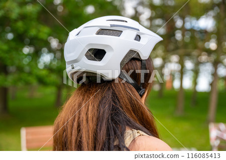 Portrait of roller skater woman putting on helmet in inline skates before rollerblading in park. Outdoor activities. Summer roller skating. Portrait of roller skater woman putting on helmet in inline skates before rollerblading in park. Outdoor activities. Summer roller skating. 116085413
