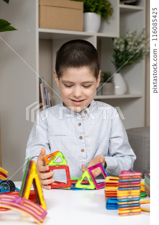 Boy builds buildings from a magnetic construction set 116085425