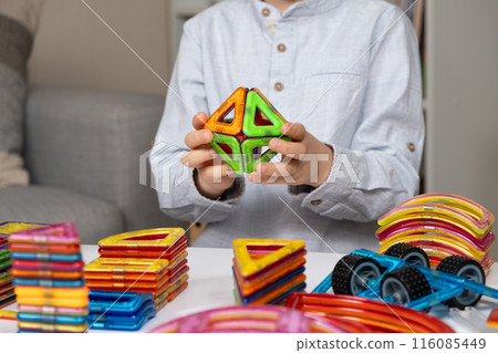 Child playing with magnetic constructor, hands close-up. 116085449