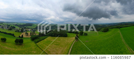 Enjoy the picturesque view of the overcast countryside with green fields and rolling hills Enjoy the picturesque view of the overcast countryside with green fields and rolling hills 116085987