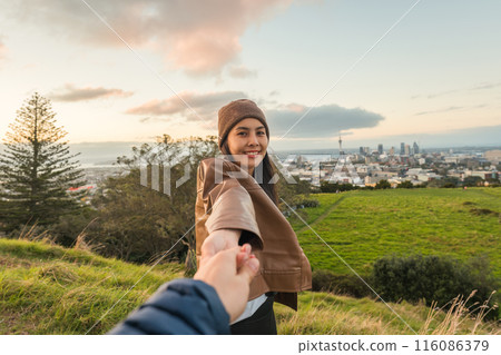 Asian woman holding hands with couple on viewpoint of city in the evening at Auckland 116086379