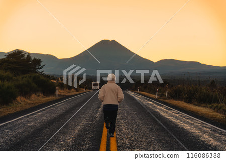 Female tourist running on the road with Mount Ngauruhoe in the morning at Tongariro national park, New Zealand 116086388
