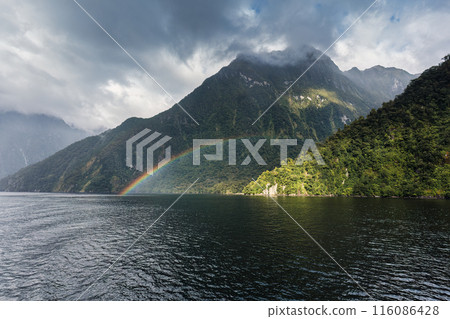 Milford Sound with rainbow over mountain lake at Fiordland national park, New Zealand 116086428