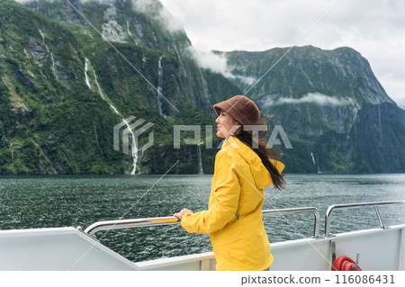 Asian woman enjoying the view of Milford Sound during ferry cruise on vacation at New Zealand 116086431