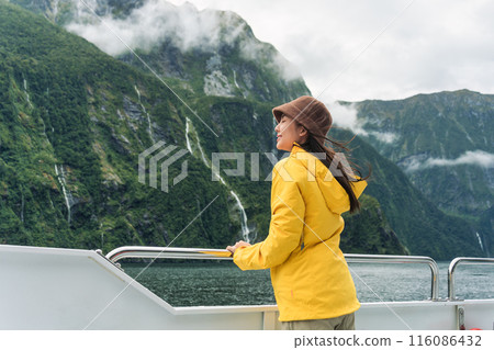 Asian woman enjoying the view of Milford Sound during ferry cruise on vacation at New Zealand 116086432