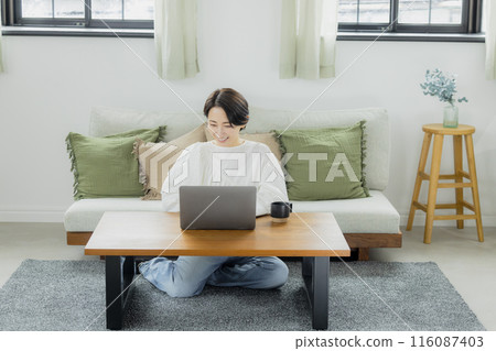 Middle-aged woman looking at a computer in the living room 116087403