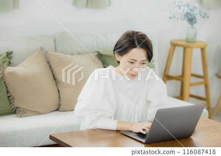 Middle-aged woman looking at a computer in the living room 116087418