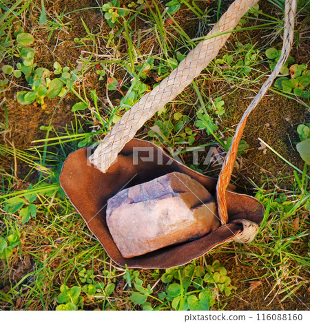 An antique leather sling lies on the ground 116088160