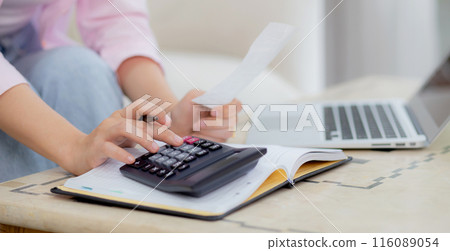 Closeup hands of woman calculating finance household with calculator on desk at home. Closeup hands of woman calculating finance household with calculator on desk at home. 116089054