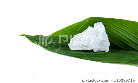White crystal clear alum cube on green leaf isolated on white background. 116089719