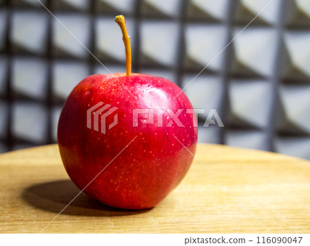 Dew-kissed red apple on wooden surface; intricate grey background. Dew-kissed red apple on wooden surface; intricate grey background. 116090047